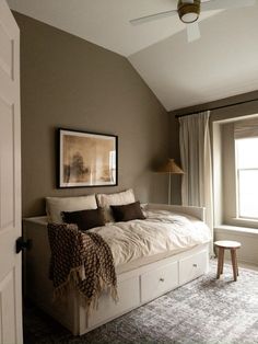 a bed sitting under a window in a bedroom