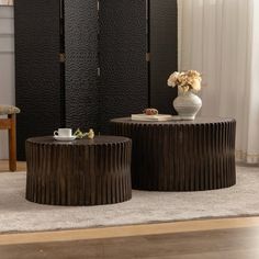 two tables sitting on top of a carpeted floor next to a vase with flowers