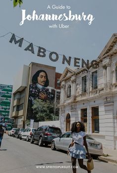 a woman walking down the street in front of a building with a mural on it