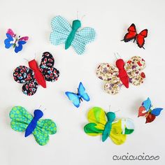 several colorful butterflies are arranged on a white surface, one is red and the other is blue