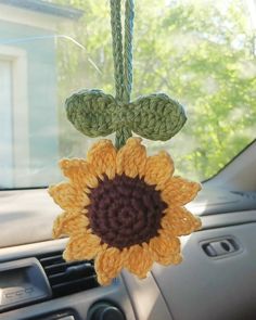 a crocheted sunflower hanging from a car dashboard