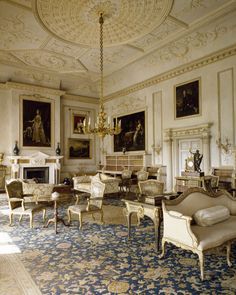 an ornately decorated living room with antique furniture and paintings on the walls, along with a chandelier