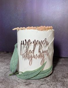 a cake that has been decorated with leaves and writing on the frosted icing