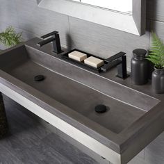 a bathroom sink with two soap dispensers on the top and a potted plant next to it