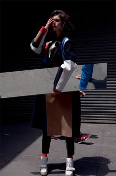 a woman is standing on the sidewalk with a cardboard box