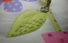 a close up of a sewing needle on a piece of fabric with flowers in the background