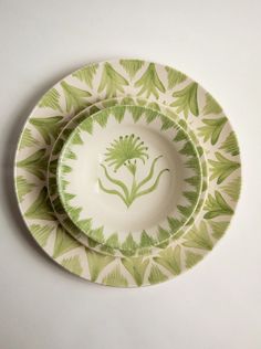 two green and white plates sitting on top of each other in front of a white wall