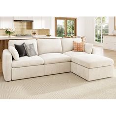 a living room with a large white sectional couch and lots of pillows on the floor