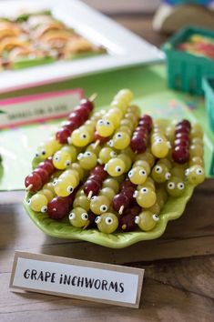 grapes are arranged in the shape of animals on a green plate with a sign that says grape incowns