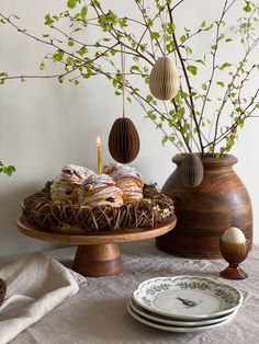 a table topped with plates and vases filled with food next to a tree branch