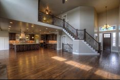 a large open floor plan with wood floors and wooden stairs leading up to the second story