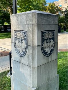 a cement monument with two crests on it in the middle of a grassy area