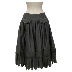 Wide pleated gray flannel skirt from the Ready to Wear Fall Winter 2010. Below the basque, on the front side, are two pockets with flap with decorative flat tablet buttons covered in the same skirt fabric. The hem is enlivened by chasing spikes. The bottom is decorated with small applied grosgrain bows from which pleated tulle fans depart. The fabric is a flannel 98% wool 2%. JOHN GALLIANO" rubber label. Never worn. Video on request. Galliano Skirt, Gray Relaxed Flared Pleated Skirt, Wide Pleated Skirt, Vintage Flared Gathered Skirt, Rubber Label, Flannel Skirt, John Galliano Fall 1994, John Galliano Fall Winter 2009, Grey Flannel