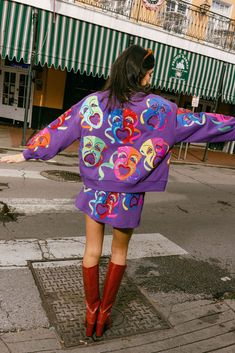 the woman is walking down the street in her colorful dress and red cowboy booties