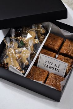 a box filled with brownies and cookies on top of a white countertop next to a black box