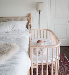 a baby laying in a crib next to a bed