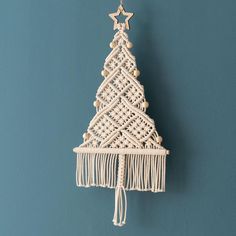 a small white christmas tree hanging on a wall with wooden beads and tassels