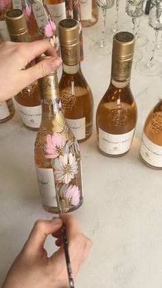 a person is holding a pen and writing on a wine bottle in front of several bottles