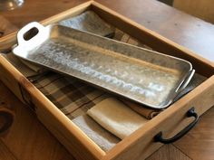 a wooden box with two trays and napkins in it on top of a table