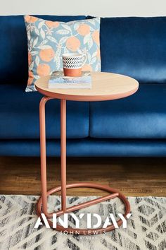 a blue couch with an orange and white pillow sitting on top of it next to a table