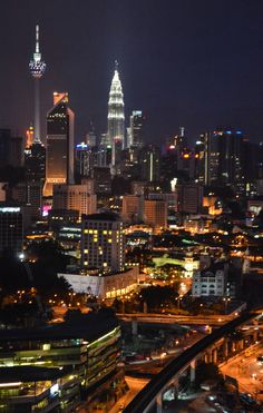 the city skyline is lit up at night with lights on and skyscrapers in the background