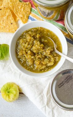 a white bowl filled with green salsa next to tortilla chips