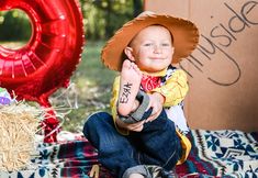 a young boy wearing a cowboy hat sitting on a blanket