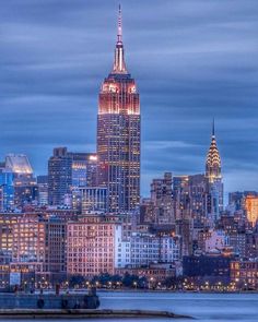 the empire state building lit up in red, white and blue at night with city lights