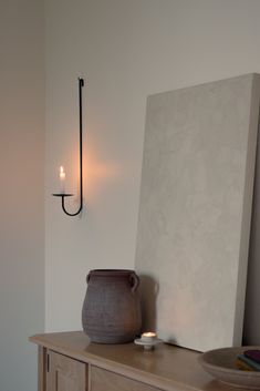 a vase sitting on top of a wooden table next to a wall mounted candle holder