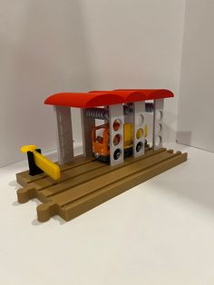 a toy gas station with two cars and a yellow car on the platform next to it