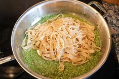 a pan filled with pasta and pesto on top of a stove