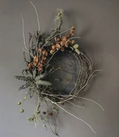 an arrangement of flowers and branches on a gray wall with a mirror in the middle