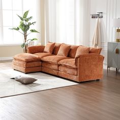 a living room with a large sectional couch and rugs on the wooden flooring