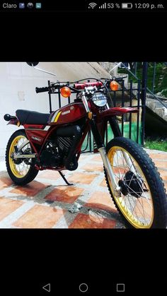 a red and yellow motorcycle parked on top of a tiled floor next to a building