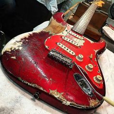 an old red guitar sitting on top of a table