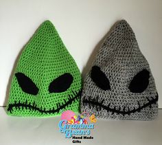 two crocheted hats with black eyes and green faces