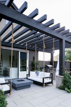 an outdoor living area with white couches and swings