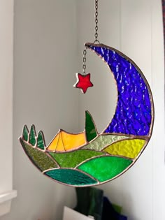 a stained glass sun catcher hanging from a chain with a star and moon on it