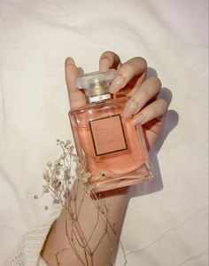 a woman's hand holding a bottle of perfume