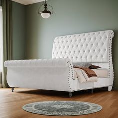 a white bed sitting on top of a hard wood floor next to a green wall