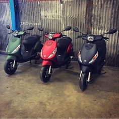 three scooters are parked next to each other in a garage with corrugated walls