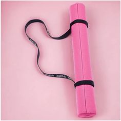 a pink yoga mat with black straps on a pink background