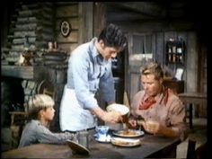 two women and one man are preparing food at the kitchen table in an old time tv show