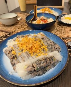 two plates with food on them sitting on a table next to bowls and utensils