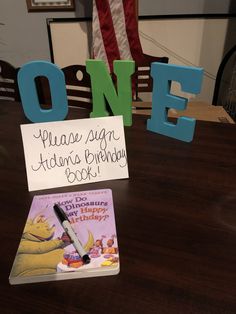 a wooden table topped with a note and a pen next to a sign that says one