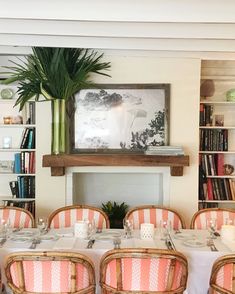 the dining room is set with pink and white tablecloths, wicker chairs, and bookshelves