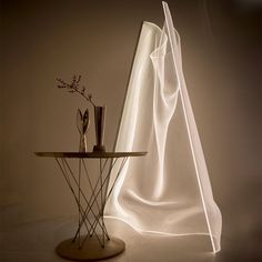 a table with a vase on it next to a white cloth draped over the table