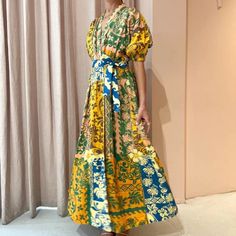 a woman standing in front of a window wearing a colorful dress