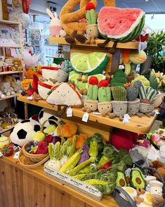 there are many stuffed animals on the shelves in this store, including watermelon and cucumbers