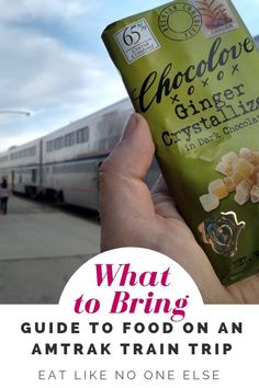 a person holding up a can of food in front of a train